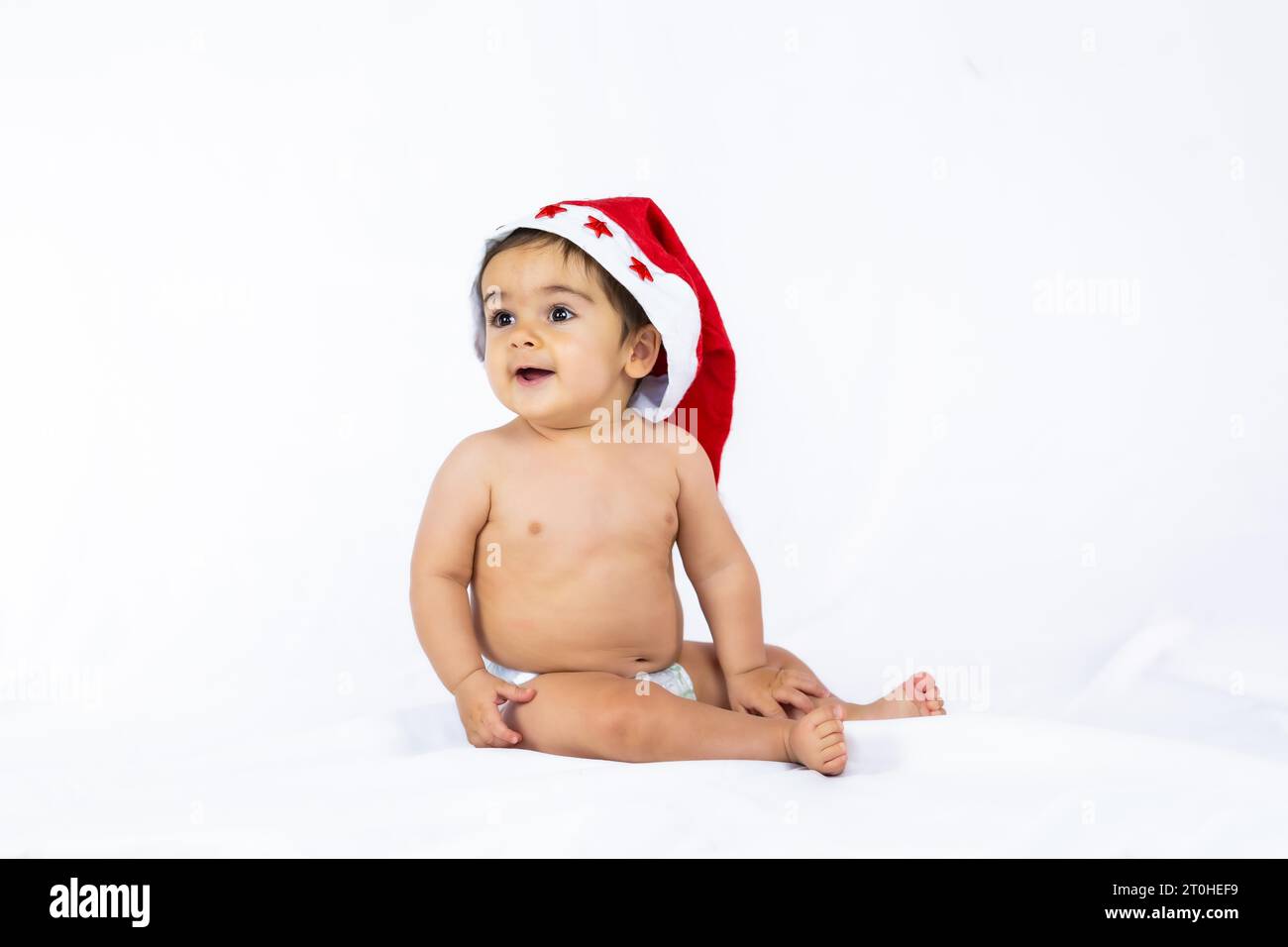 Un niño pequeño con un sombrero rojo de Navidad sobre un fondo blanco, espacio de copia Foto de stock