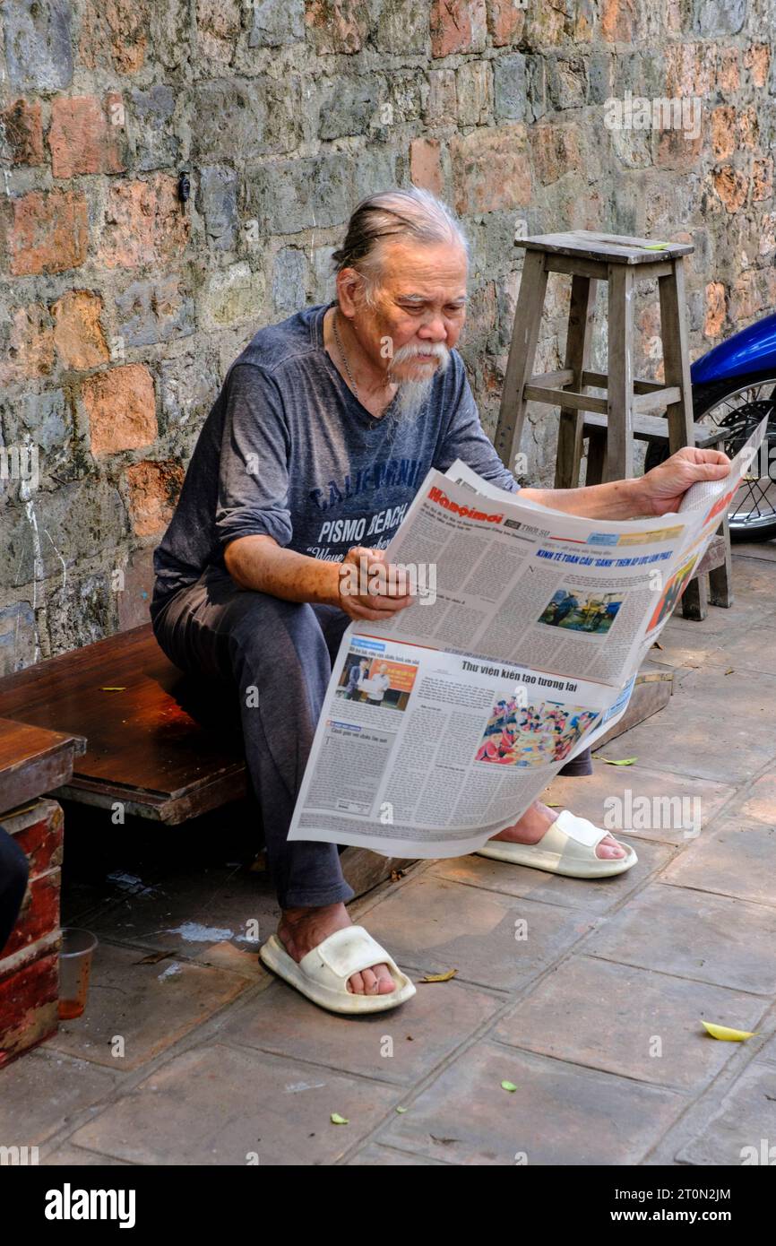 Hanoi, Vietnam. Anciano leyendo un periódico. Foto de stock