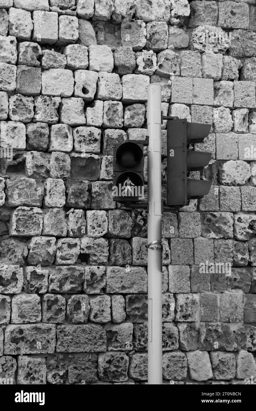 La luz de cruce peatonal en blanco y negro se volvió verde contra una pared de fondo de piedra de ladrillo. Concepto de comunicación y seguridad Foto de stock