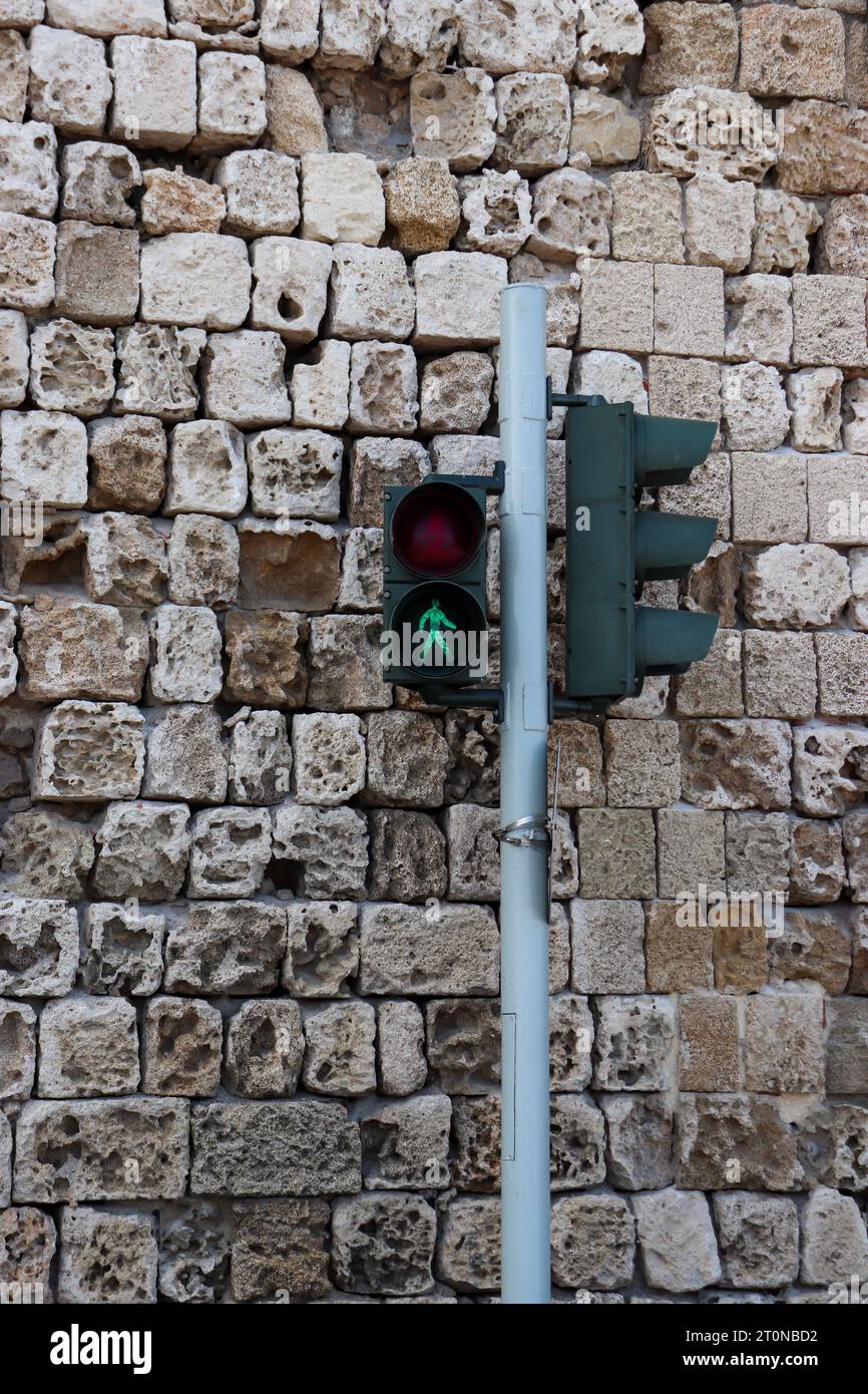 La luz de cruce peatonal se volvió verde contra una pared de fondo de piedra de ladrillo. Concepto de comunicación y seguridad Foto de stock