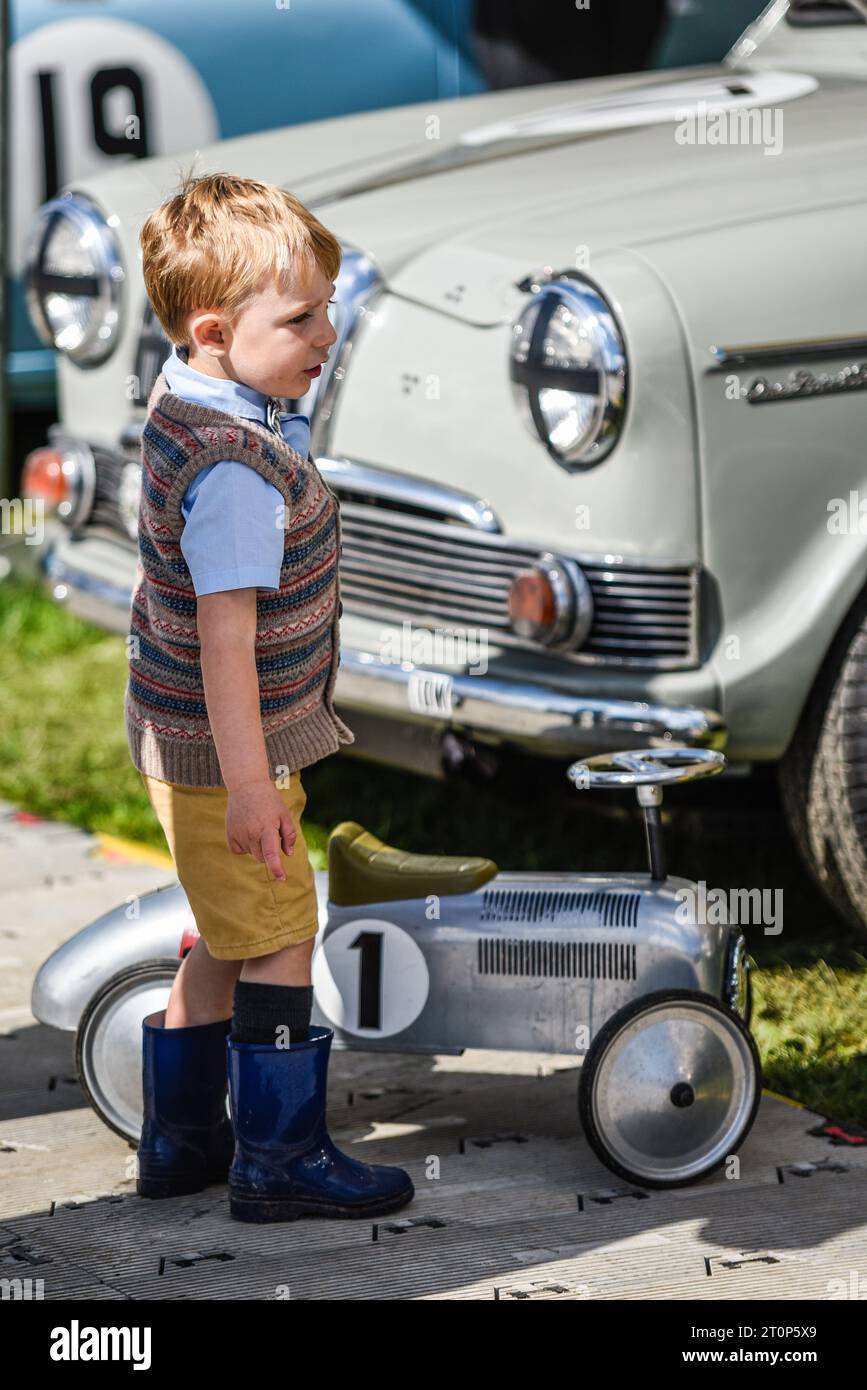 Un niño con traje vintage con un coche de juguete grande clásico, junto con un vehículo clásico de tamaño completo en el evento de nostalgia de Goodwood Revival. Retroactivo Foto de stock