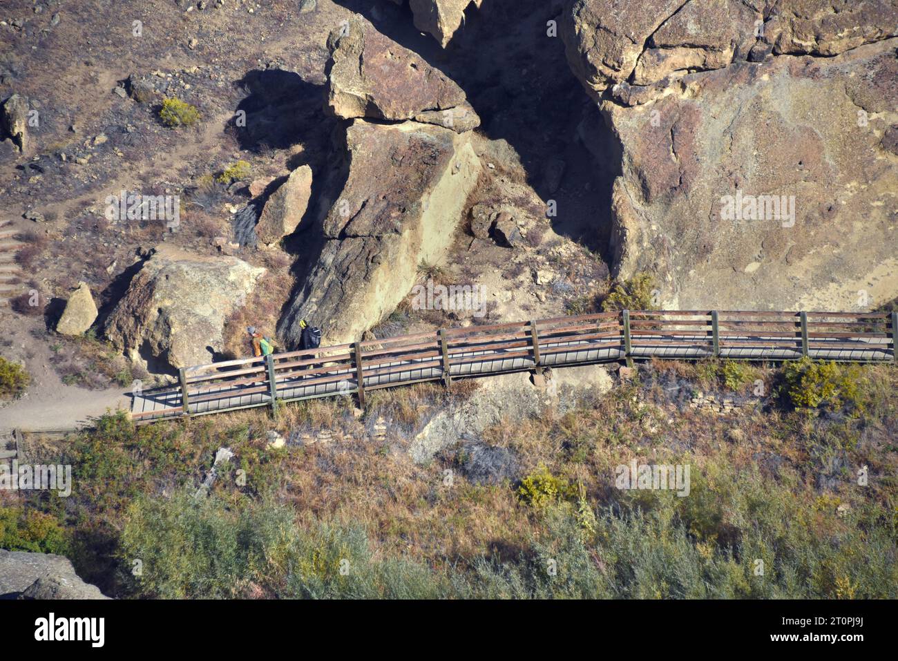Dos escaladores cruzan el puente pedestrain en Smith Rock State Park en Oregon. Están llevando el equipo en sus espaldas mientras caminan a la escalada Foto de stock