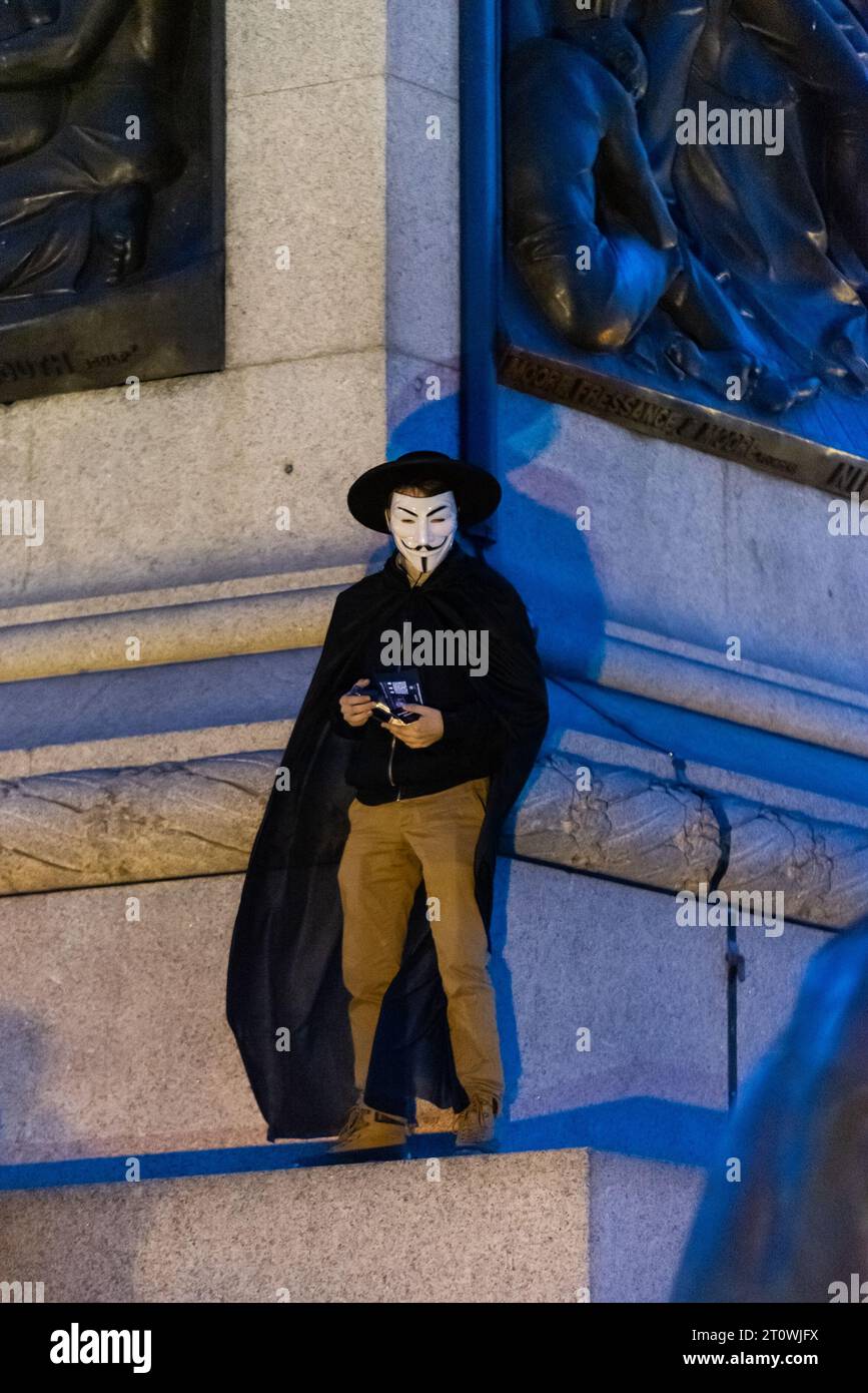 Millones de máscaras marchan Londres, por Anonymous para los sin voz. Activista con la máscara V para Vendetta con el estilo de Guy Fawkes, en la columna de Nelson Foto de stock