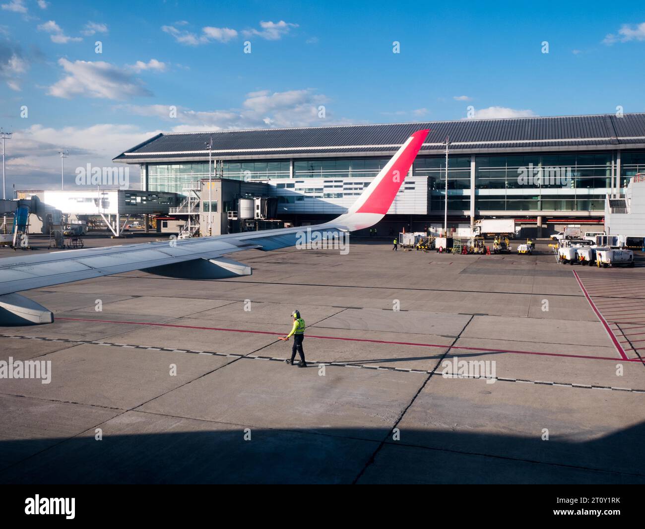 trabajador que lleva equipo de seguridad guiando un avión durante el rodaje para despegar con el ala sobre el hombre Foto de stock