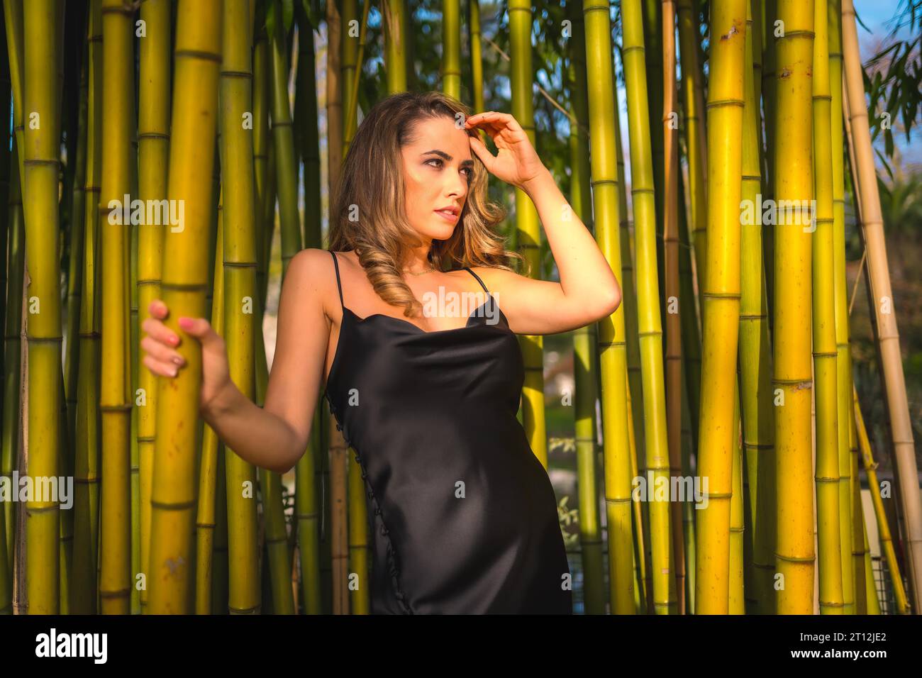 Retrato de una niña caucásica en un vestido negro en un bosque de bambú Foto de stock