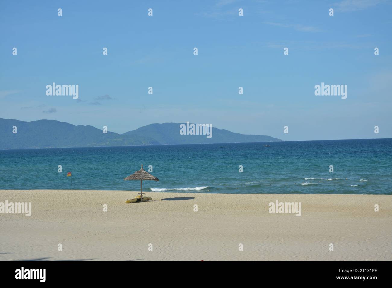 playa marrón y sombrilla de paja en la tarde soleada Foto de stock