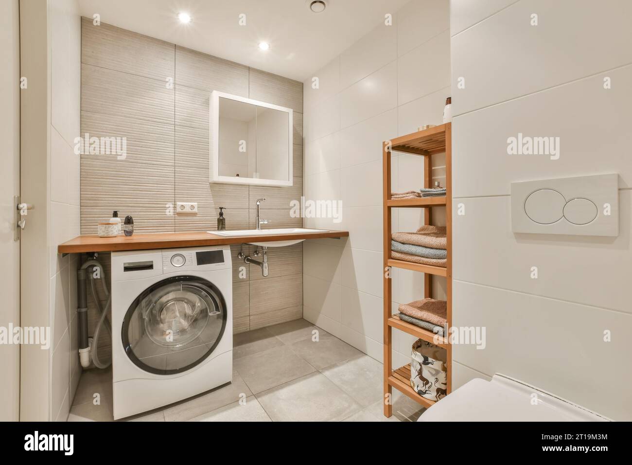 una pequeña sala de lavandería con una lavadora y secadora en la esquina,  hay un estante de madera en la pared Fotografía de stock - Alamy