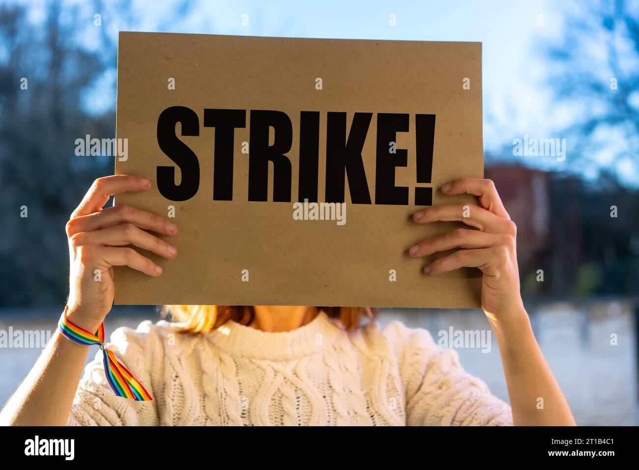 Una activista sosteniendo un cartel con el eslogan de los actores y escritores de hollywood golpean con el cielo azul en el fondo Foto de stock