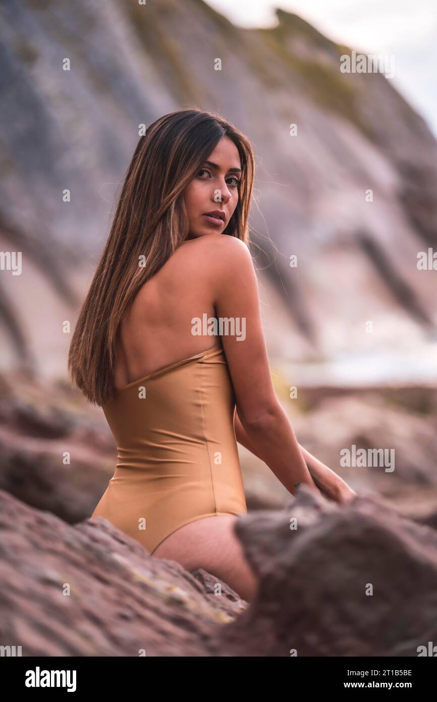 Retrato de una mujer morena con un traje de baño en una playa en verano, junto a las rocas Foto de stock