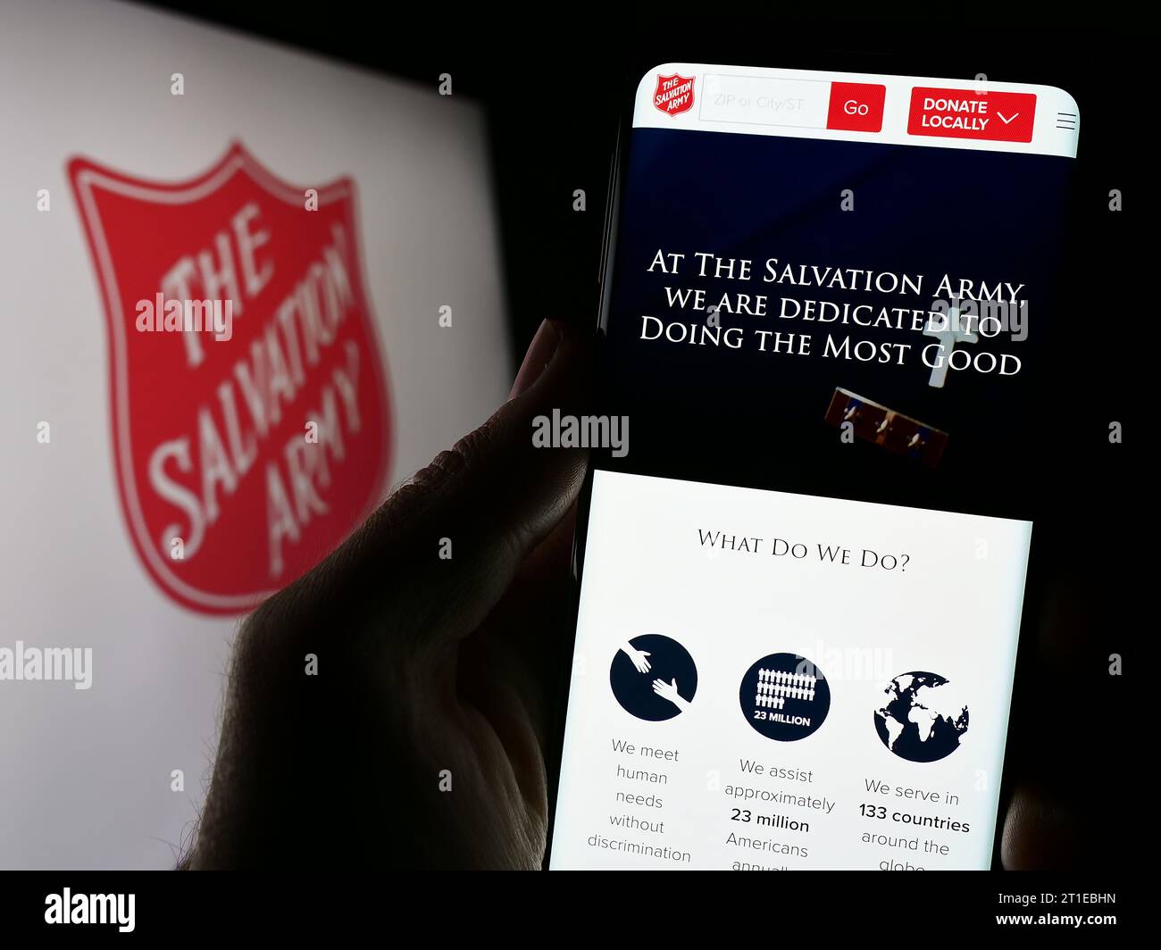 Persona que sostiene el teléfono inteligente con el sitio web de la organización de caridad protestante El Ejército de Salvación (TSA) con el logotipo. Enfoque en el centro de la pantalla del teléfono. Foto de stock