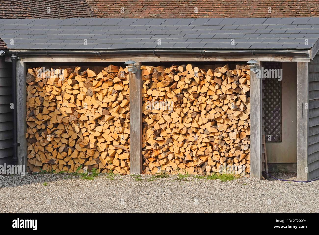 Estructura inclinada y protección de techo inclinado para cortar troncos de madera almacenados al aire libre para el invierno en la casa pública de Essex Inglaterra Reino Unido Foto de stock