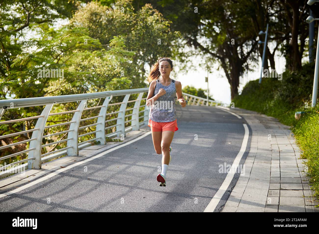 mujer asiática joven corriendo corriendo al aire libre en el parque Foto de stock