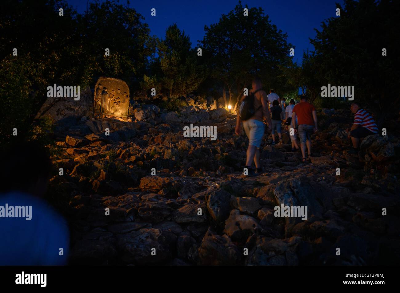 Monte Podbrdo en Medjugorje por la noche. La gente está ascendiendo y rezando el rosario. La escultura: Cuarto Misterio Gozoso – La Presentación de Jesús. Foto de stock