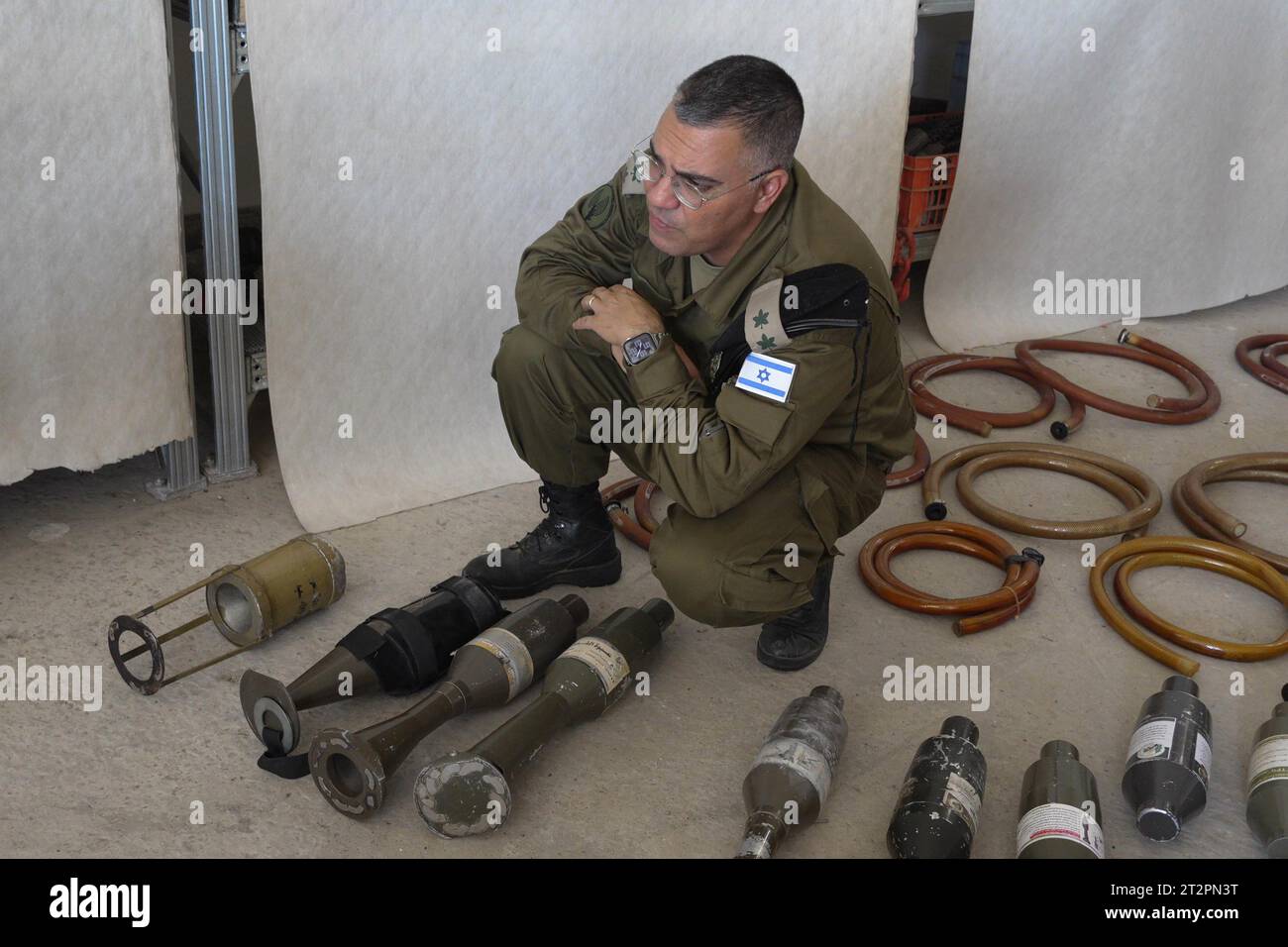 Avichay Adraee Jefe de la Unidad de Portavoz de las FDI se arrodilla junto al equipo militar y municiones que Hamás y militantes palestinos usaron dentro de Israel durante el ataque del 7 de octubre 20 de 2023 en Kiryat Malakhi, Israel. Foto de stock