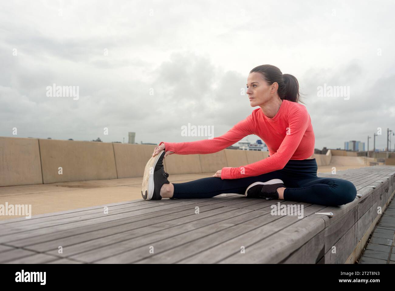 Mujer deportiva haciendo ejercicios de estiramiento de piernas, afuera. Entrenamiento al aire libre. Foto de stock