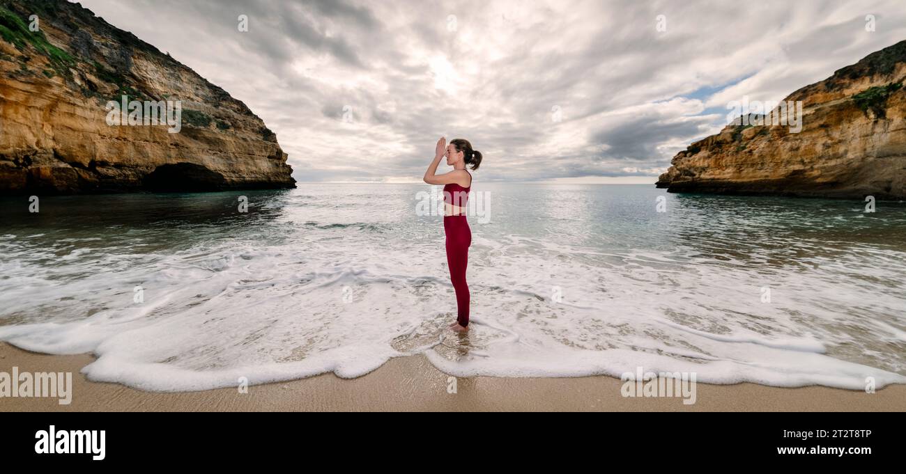 Mujer de pie en el mar practicando yoga y meditación. Alejarse de todo. Foto de stock