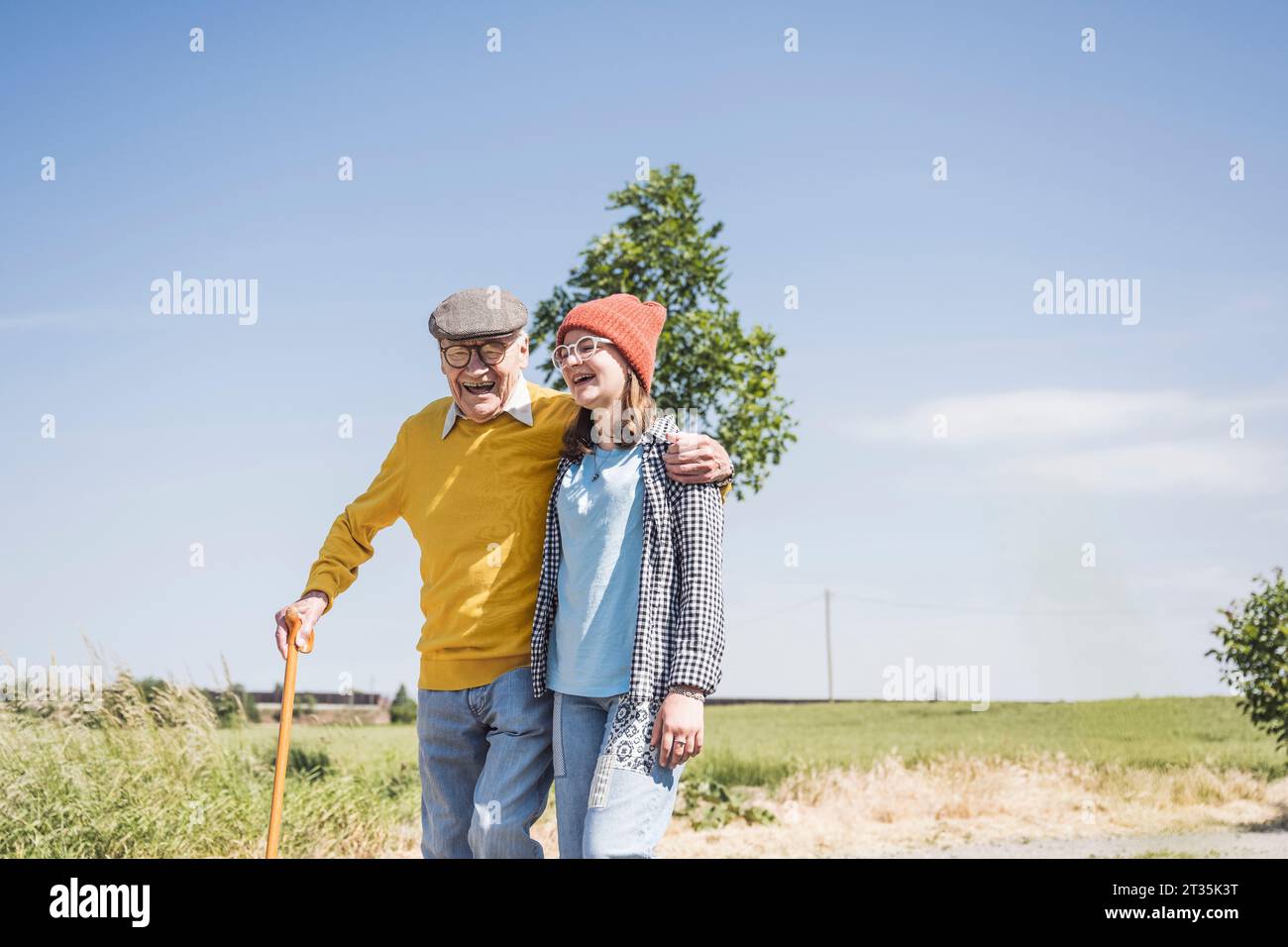 Hombre mayor feliz que camina con la nieta en día soleado Foto de stock