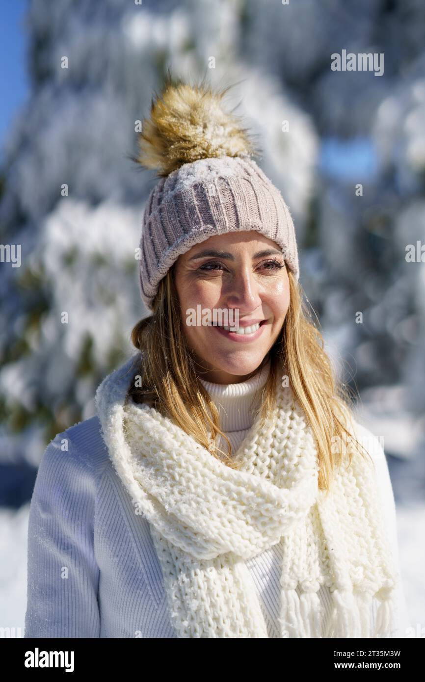 Mujer sonriente con traje blanco y gorra en la nieve del invierno Foto de stock
