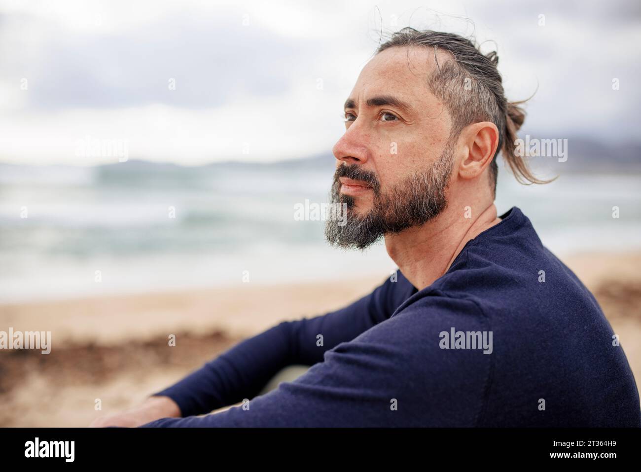 Hombre contemplativo con camiseta azul en la playa Foto de stock