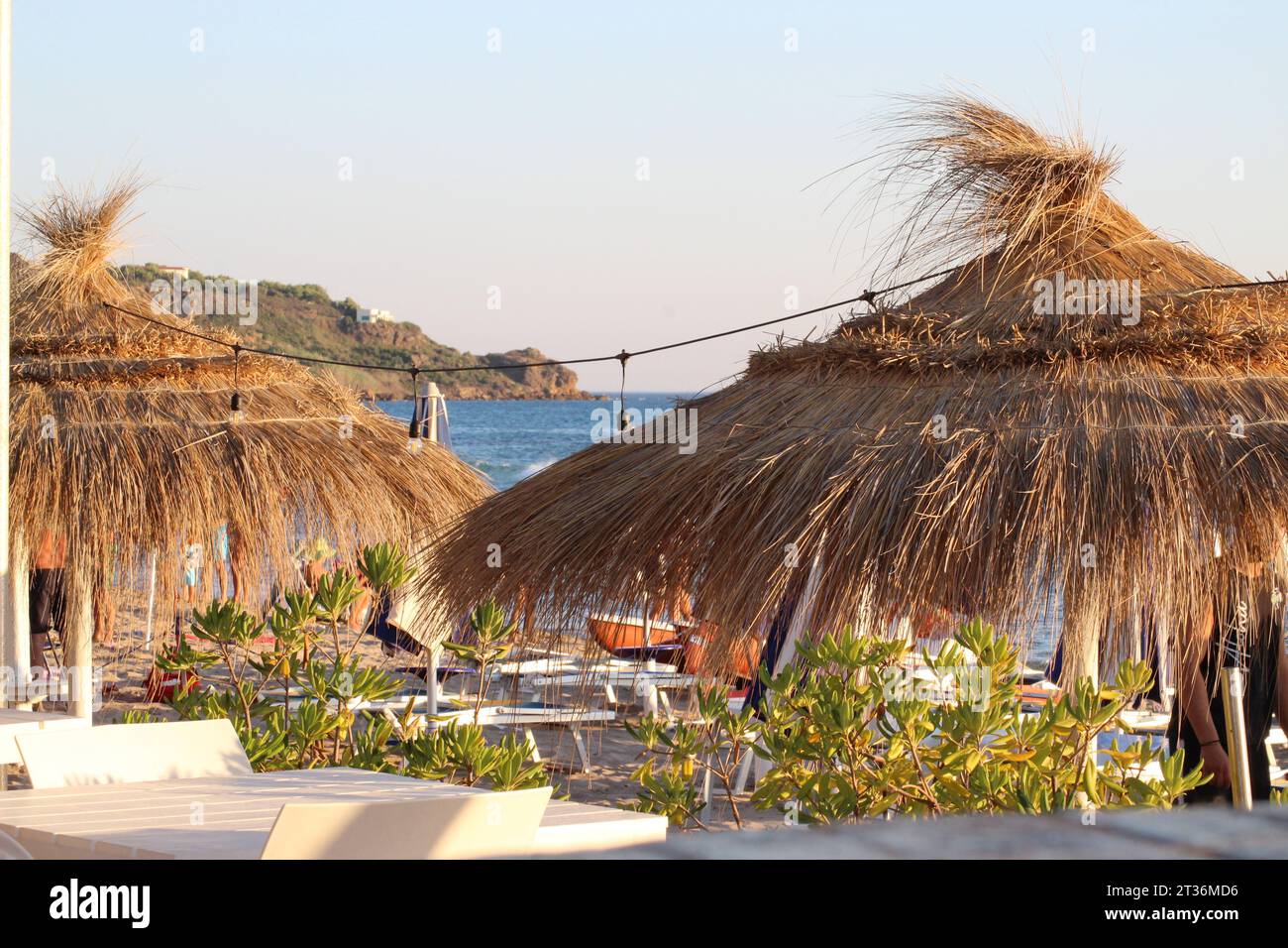 Vista de sombrillas de paja y la costa en la playa de San Marco en Sciacca Sicilia con luz de la puesta de sol de verano Foto de stock