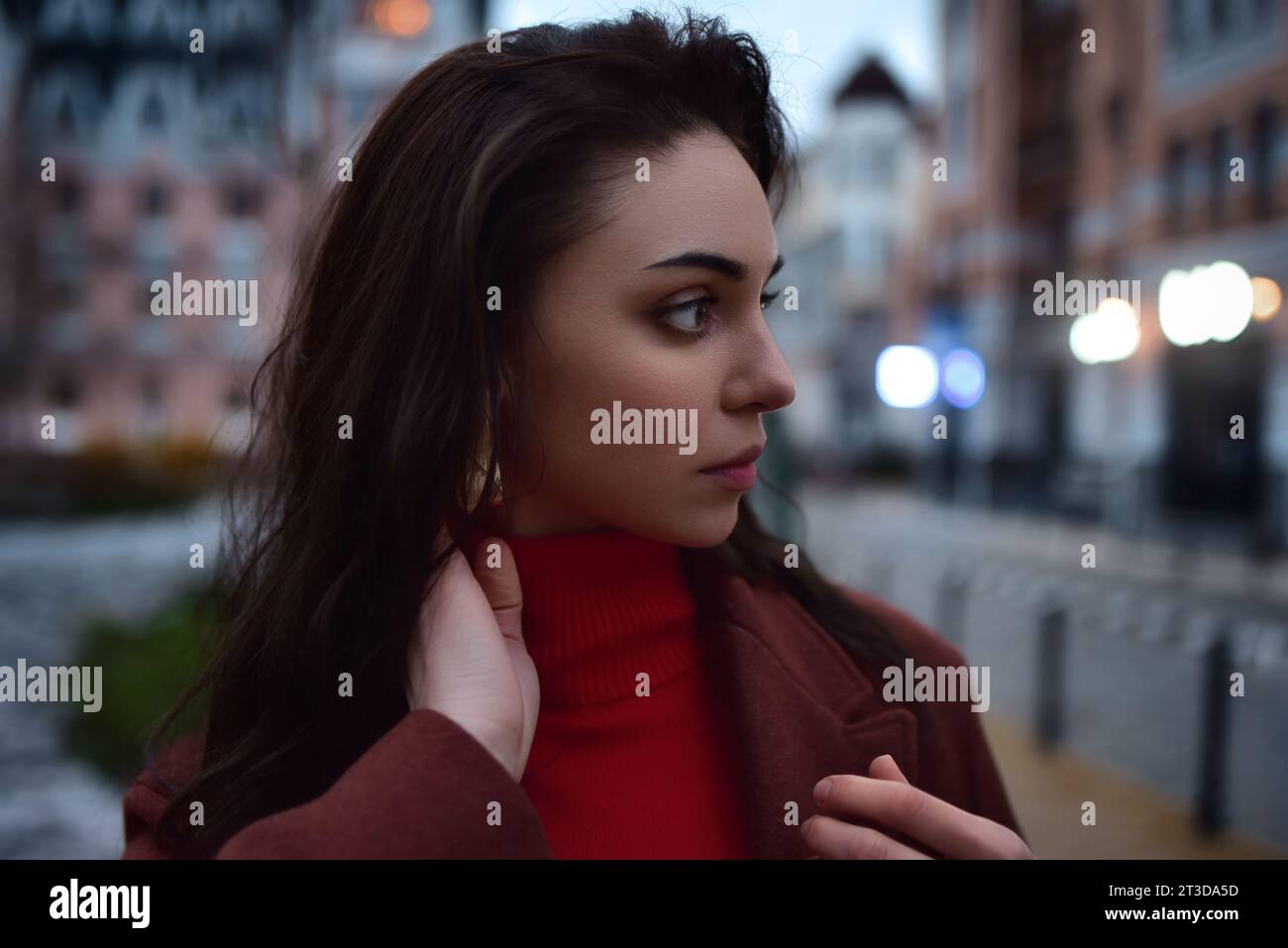 Retrato de cerca dramático de la mujer hermosa joven que mira a un lado contra el fondo de la ciudad de la noche Foto de stock