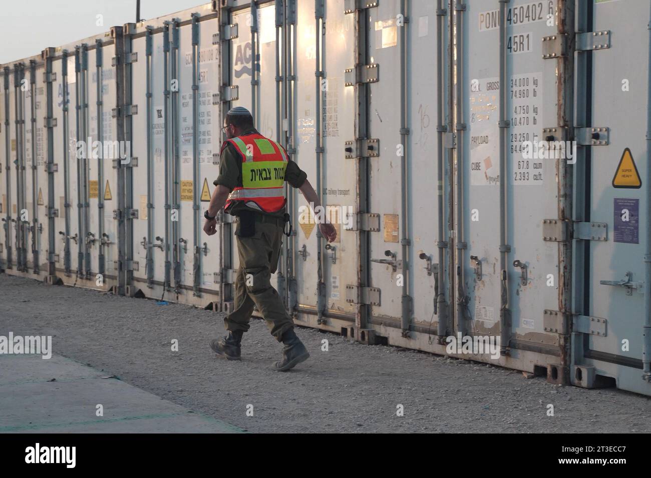 Un soldado de la unidad de rabinatos militares camina junto a contenedores refrigerados llenos de cadáveres de civiles israelíes muertos en el ataque sin precedentes de Hamás contra comunidades cercanas a Gaza hace más de dos semanas en una instalación en la base militar de Shura, donde los fallecidos son recogidos e identificados el 24 de octubre. 2023 en Ramla, Israel. Foto de stock
