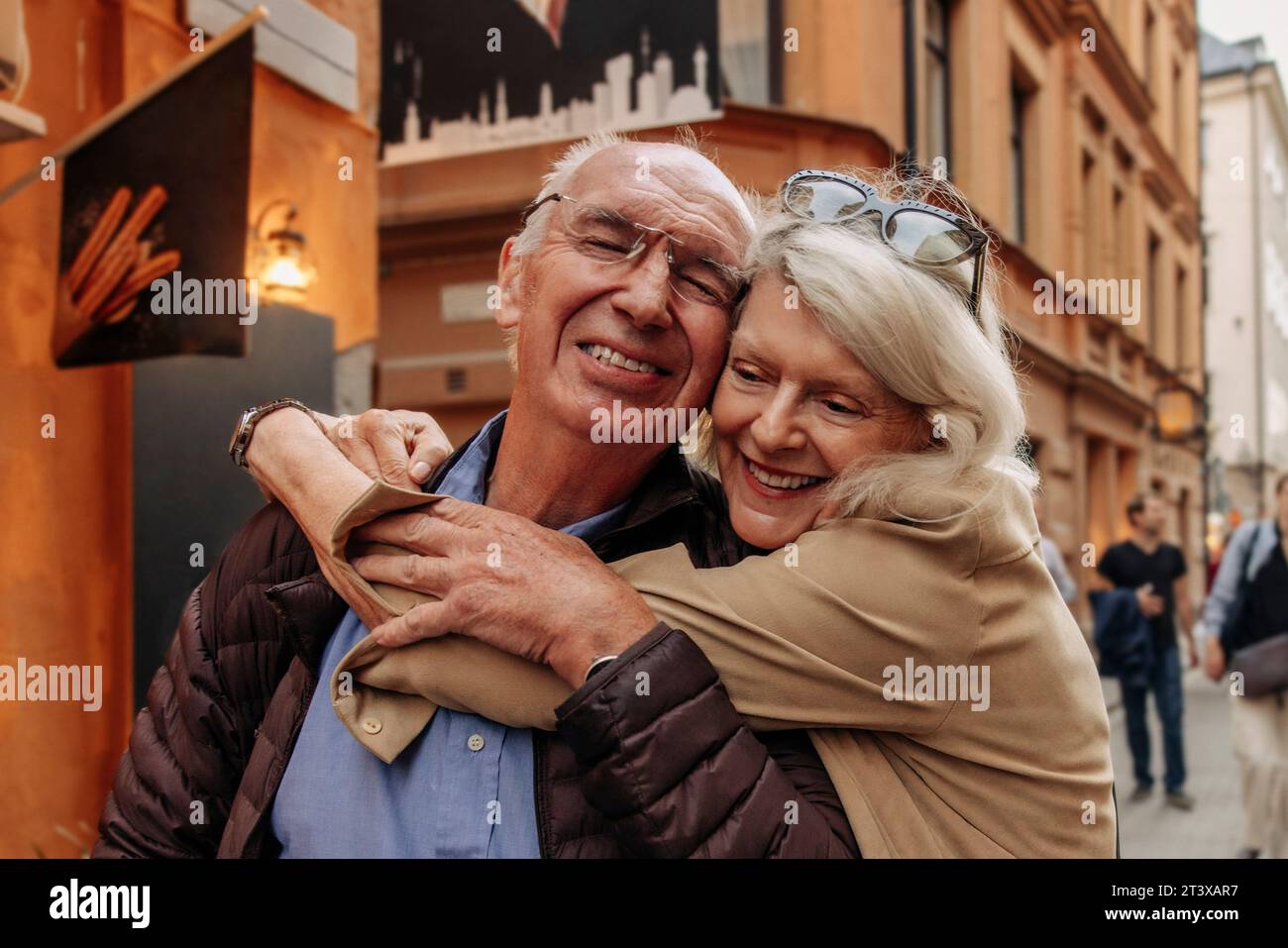 Mujer mayor feliz abrazando al hombre por detrás en la ciudad Foto de stock