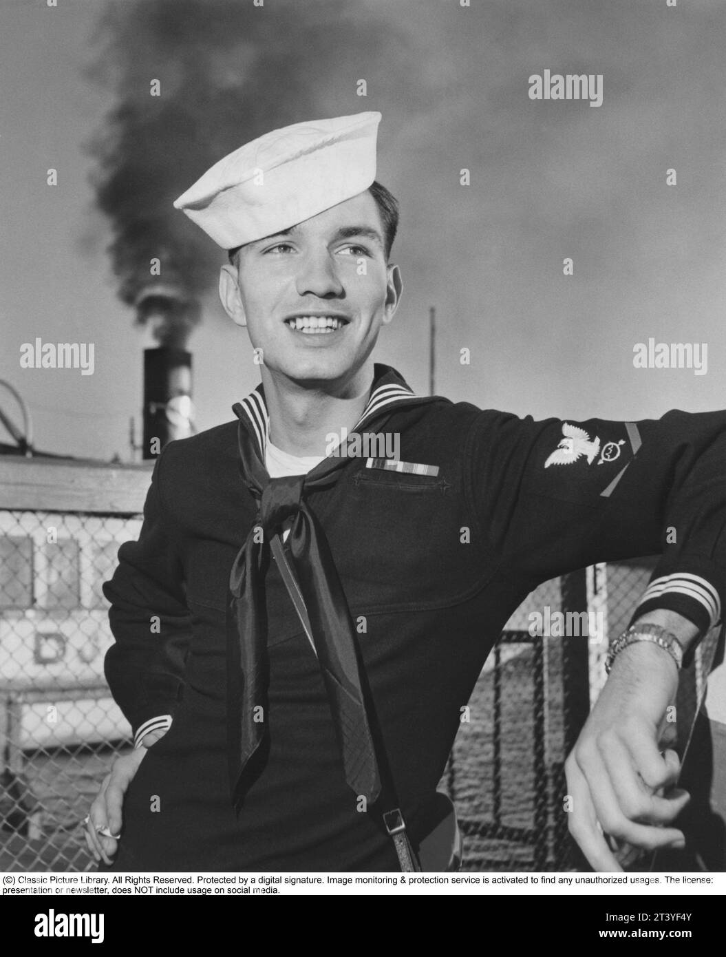 La flota estadounidense visita el 1954 de agosto. Un marinero estadounidense en Estocolmo en relación con el buque USS Baltimore de la Sexta Flota Americana a la que pertenece, está visitando la capital sueca. El nombre del marinero es Ronald Eugene Henn de Warren, Ohio, EE.UU., nacido el 29 de diciembre de 1931, muerto el 26 de diciembre de 2001. 2000.- Está posando para el fotógrafo vistiendo su uniforme y sombrero y con una sonrisa encantadora. Suecia 1954. A cargo de Anders Svahn Foto de stock