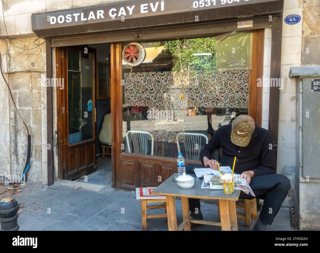 Gaziantep Turquía: Hombre leyendo periódico en la casa de té tradicional, chai diner, chai café con mesas al aire libre. Foto de stock
