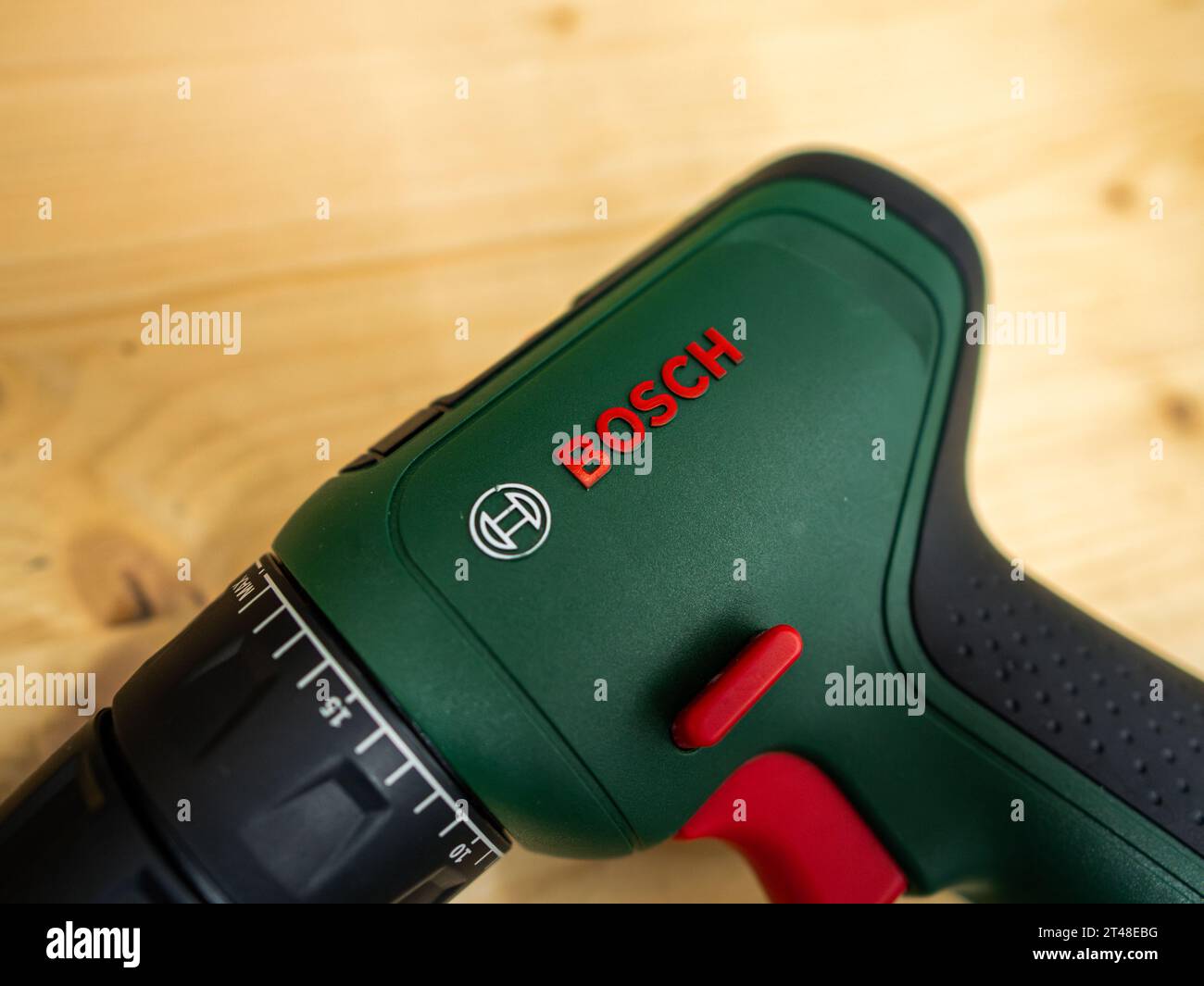 Signo con el logotipo de Bosch en un taladro inalámbrico verde. El dispositivo eléctrico para los artesanos está tumbado en una mesa de madera. Es equipo en un taller de garaje. Foto de stock