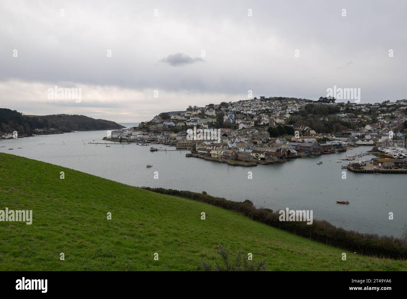 Vista de la ciudad de Salcombe, tomada en un tranquilo día de invierno que muestra el puerto, la iglesia y el barco de vida con East Portlemouth y el mar en la distancia Foto de stock