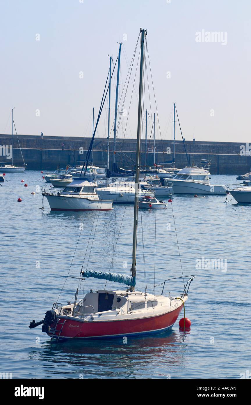Una vista pintoresca de aguas serenas con veleros atracados con gracia en el puerto Foto de stock