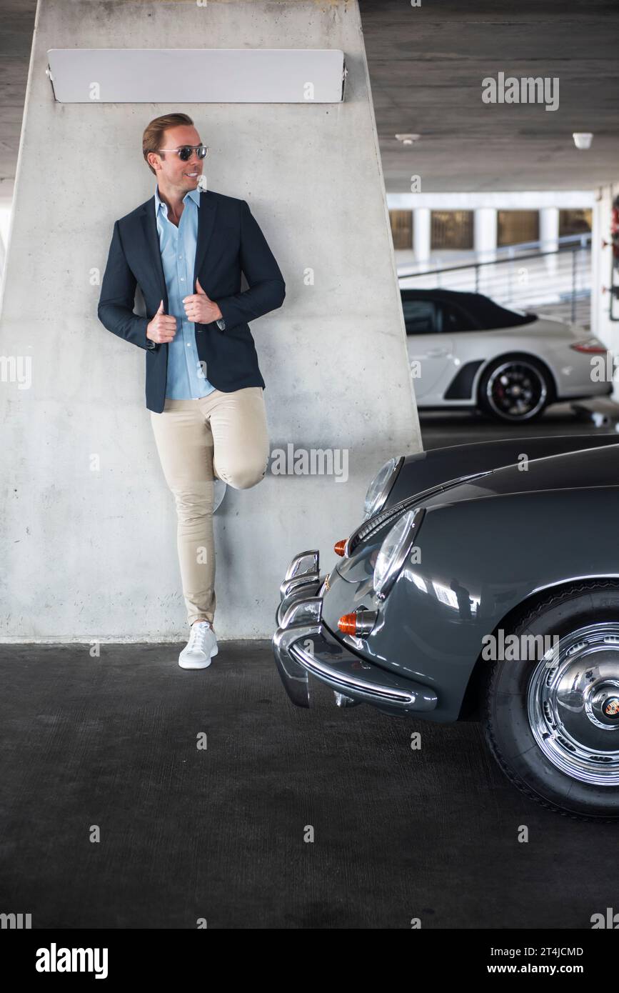 Hombre guapo posando junto a un coche vintage Foto de stock