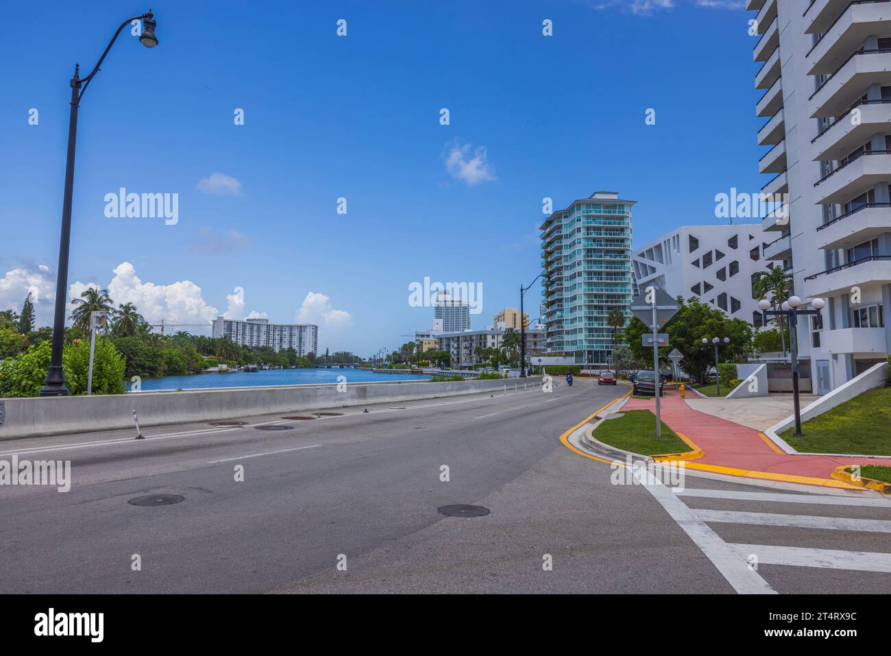 Hermosa vista de una de las calles de Miami Beach con casas junto a la carretera y el cuerpo de agua, contra el telón de fondo de cielo azul con nubes blancas. ESTADOS UNIDOS. Foto de stock