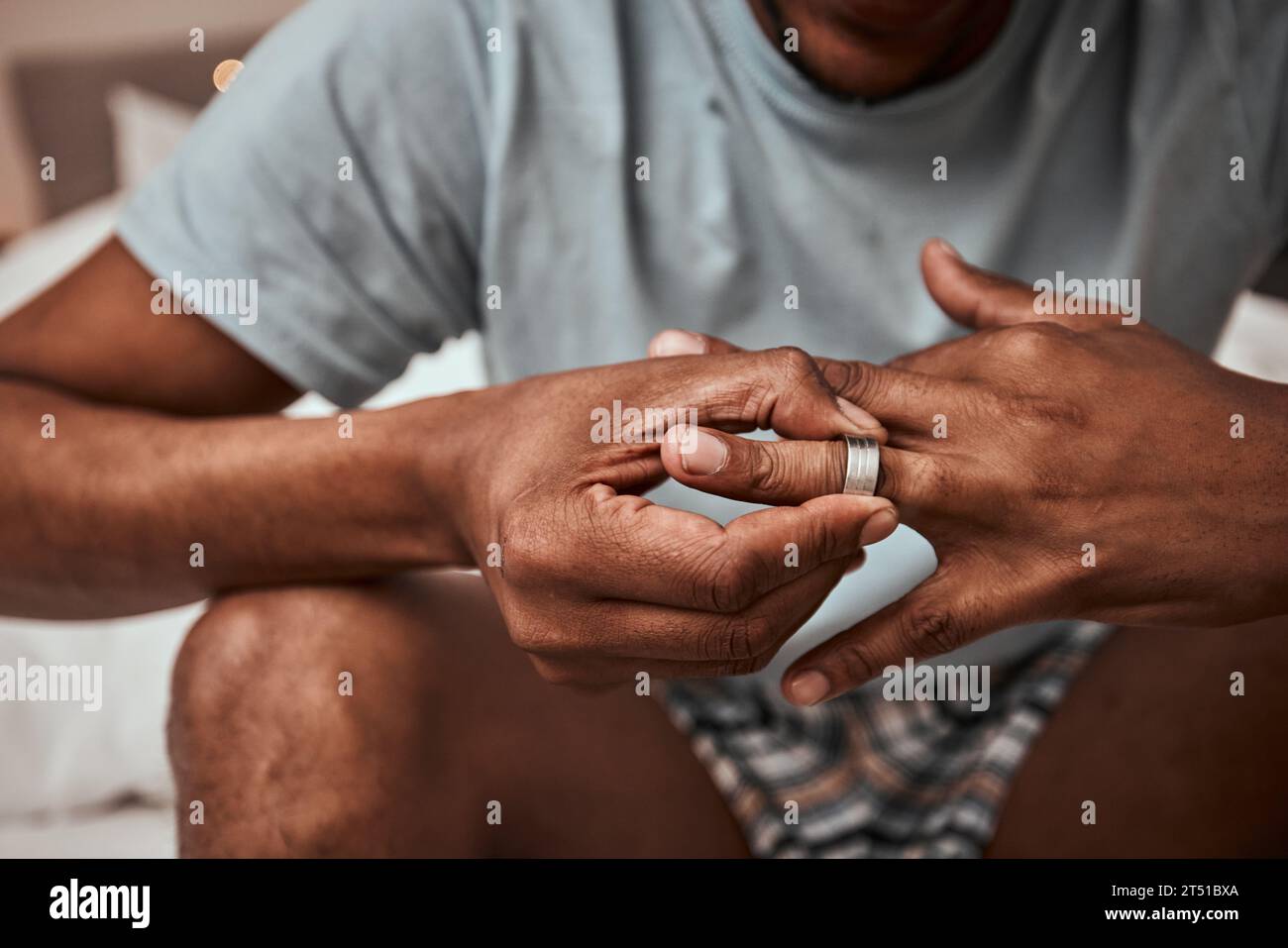 Divorcio, ruptura y anillo de boda con las manos de la persona en el dormitorio para la lucha, el conflicto y triste. Joyería, duda y romance con el primer plano del hombre y. Foto de stock