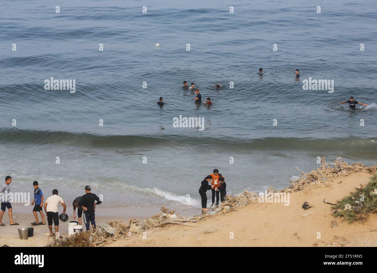 Los palestinos se reúnen en la playa para bañarse, lavar la ropa y lavar los utensilios de cocina con agua de mar debido a la falta de agua dulce y electricidad, a lo largo de la playa de Deir el-Balah, en el sur de la Franja de Gaza, el 2 de noviembre de 2023, en medio de las batallas en curso entre Israel y el grupo palestino Hamas. Israel golpeó Gaza, gobernada por Hamás, el 29 de octubre, en una creciente campaña aérea y terrestre, mientras la ONU advirtió que el orden civil estaba "empezando a derrumbarse" en el asediado territorio palestino. Miles de civiles, tanto palestinos como israelíes, han muerto desde el 2 de noviembre de 2023, después de la muerte de Palestina Foto de stock