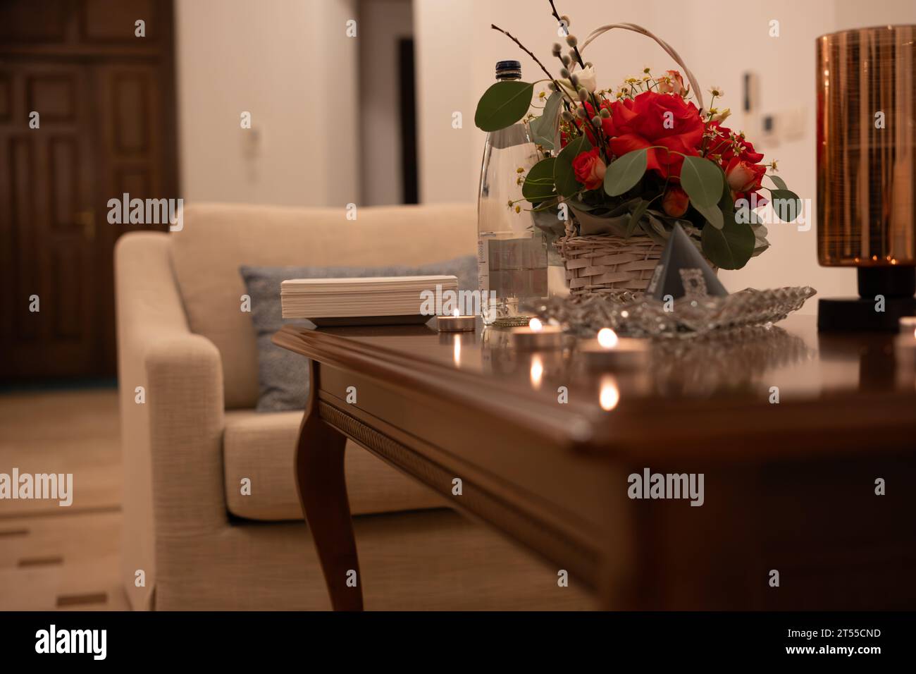 Rosas rojas en el jarrón en la mesa de madera en la sala de estar Foto de stock