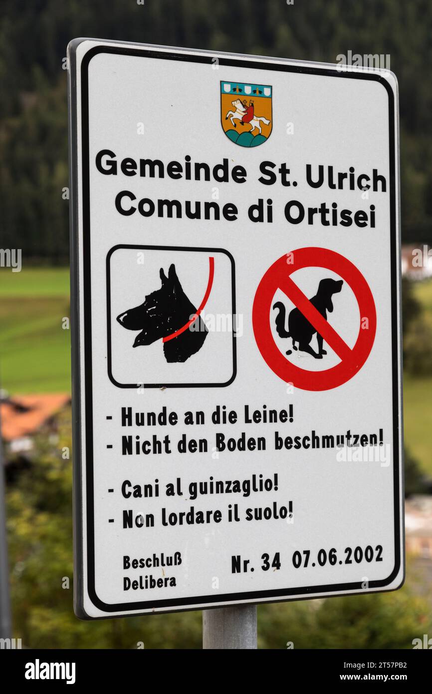 Alemán e italiano solicitando a los dueños de perros que mantengan a los perros en un plomo y no ensucien el pavimento, Ortisei, Italia Foto de stock