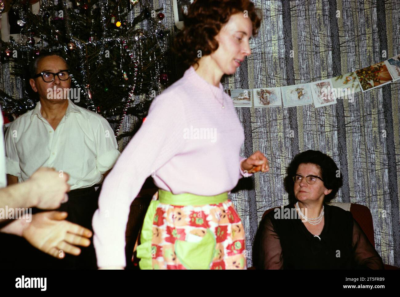 Mujer bailando, familia y amigos Navidad o fiesta de Año Nuevo, 1965-1966 Foto de stock