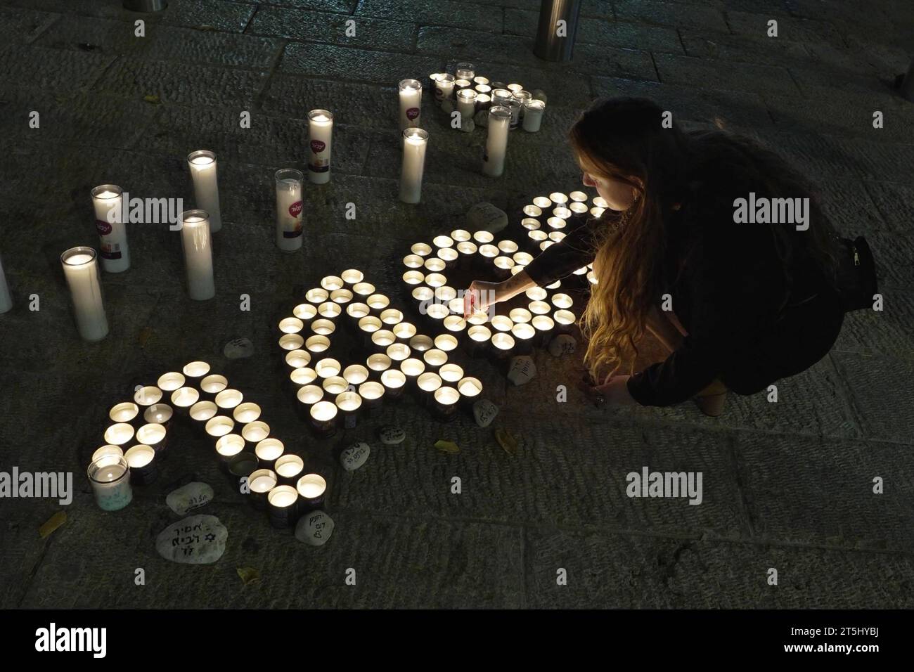 La gente enciende velas conmemorativas que marcan 30 días desde la masacre perpetrada por militantes de Hamás en comunidades cercanas a la frontera de Gaza, en la que murieron 1.400 personas y unas 240 fueron secuestradas, frente al ayuntamiento el 5 de noviembre de 2023 en Jerusalén, Israel Foto de stock