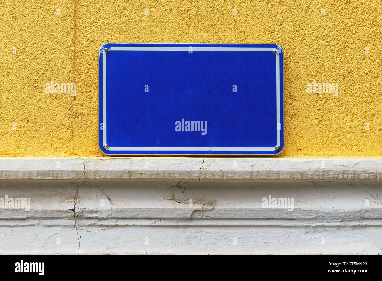 Placa de letrero de nombre de calle, placa metálica azul en pared amarilla vieja, espacio de copia de maqueta y elemento de diseño Foto de stock