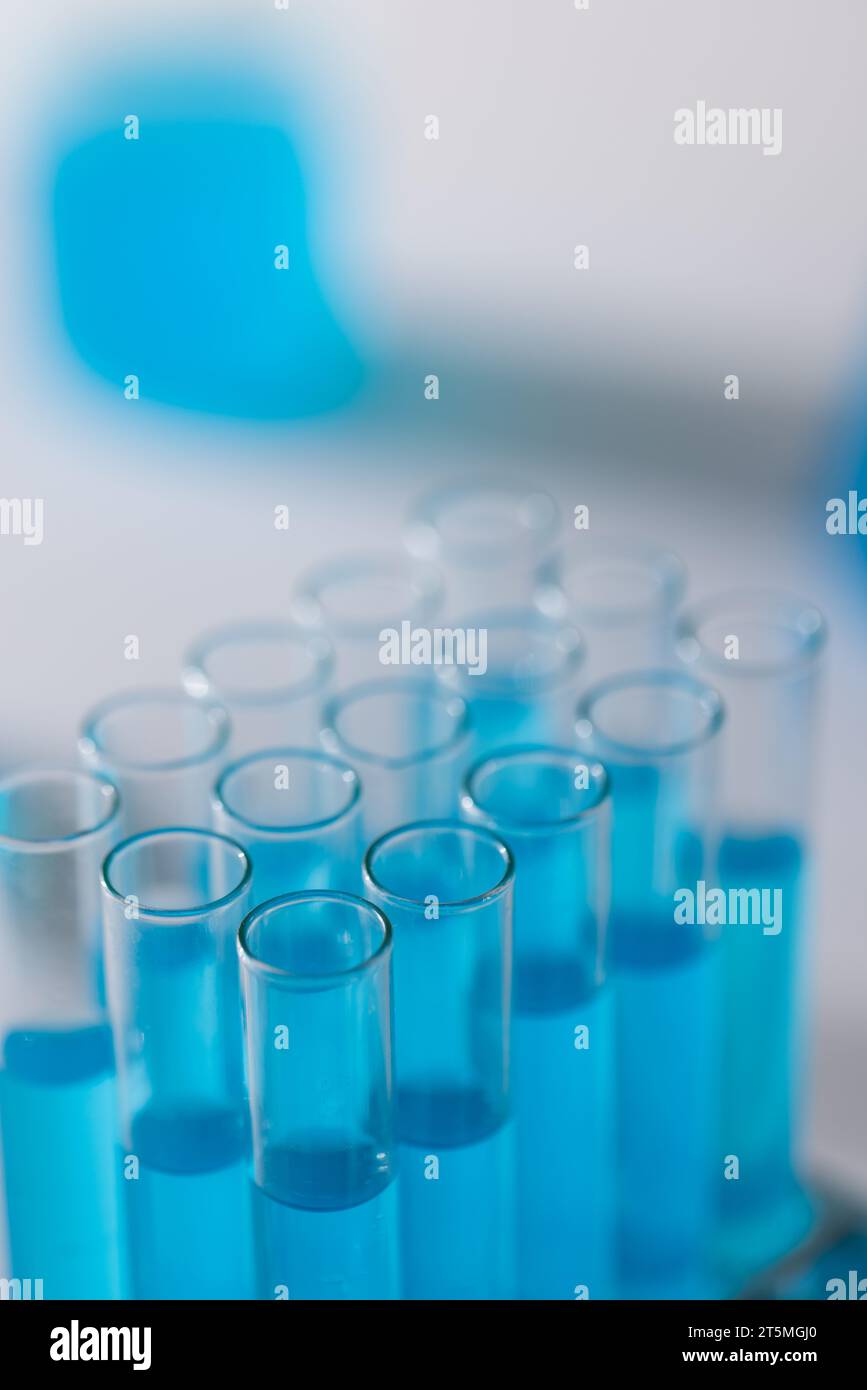 Imagen vertical de tubos de prueba de laboratorio con líquido azul y espacio de copia sobre fondo blanco Foto de stock