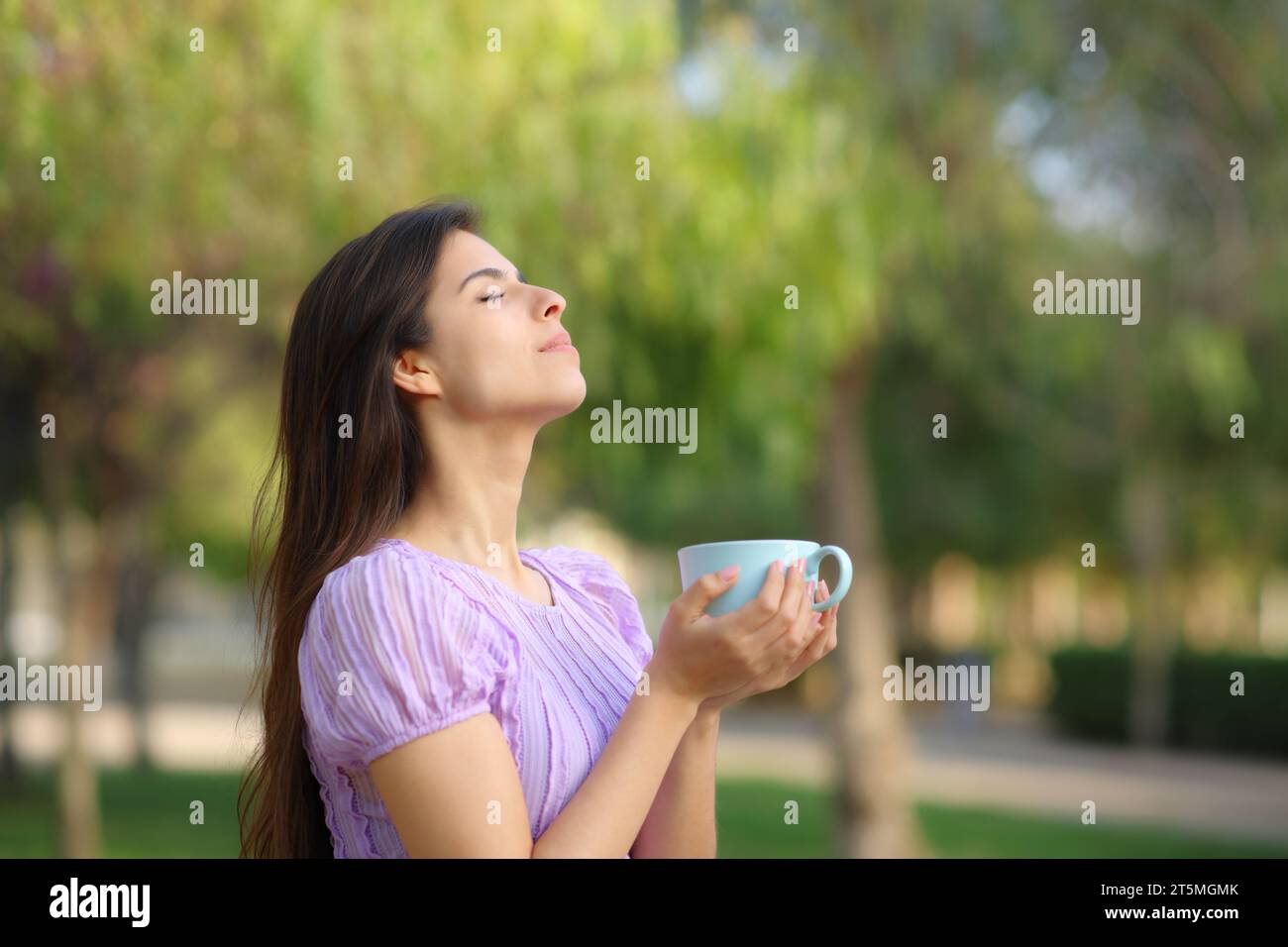 Perfil de una mujer respirando tomando café en un parque verde Foto de stock