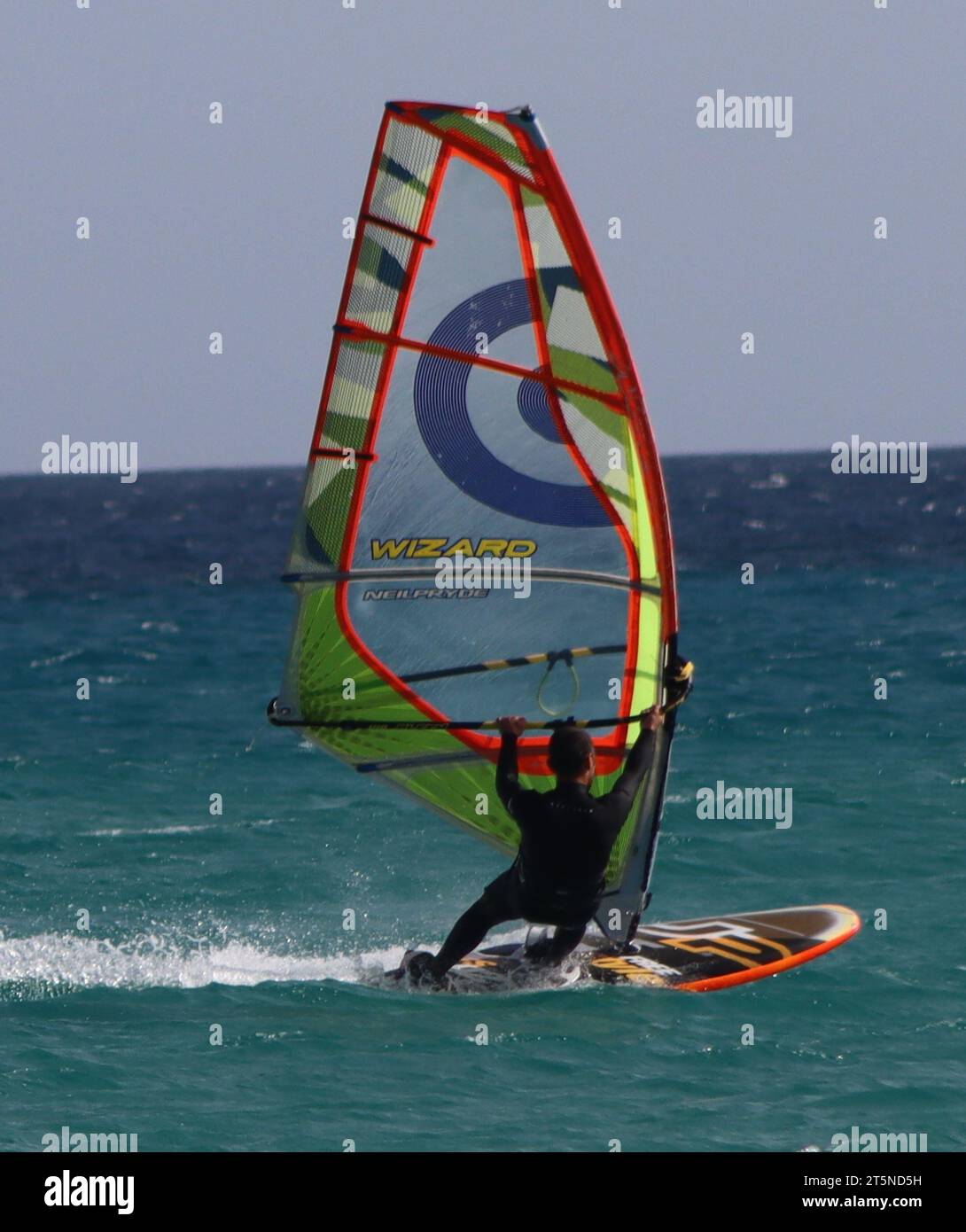 Un joven windsurf frente a la costa de la playa de Sotavento en el sur de Fuerteventura. Foto de stock