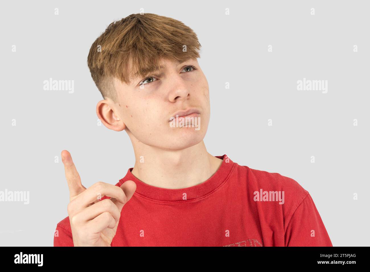 Un retrato de estudio de un adolescente pensante de quince años apuntando hacia arriba Foto de stock