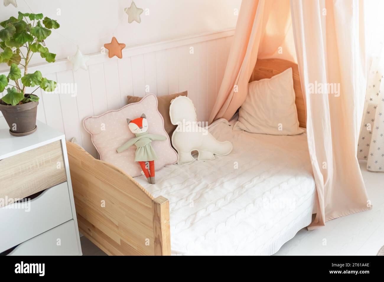 Una cama infantil acogedora y brillante con un dosel tiene lindos juguetes  suaves en la cama. Hay una planta verde al lado de la cama. fondo claro  Fotografía de stock - Alamy