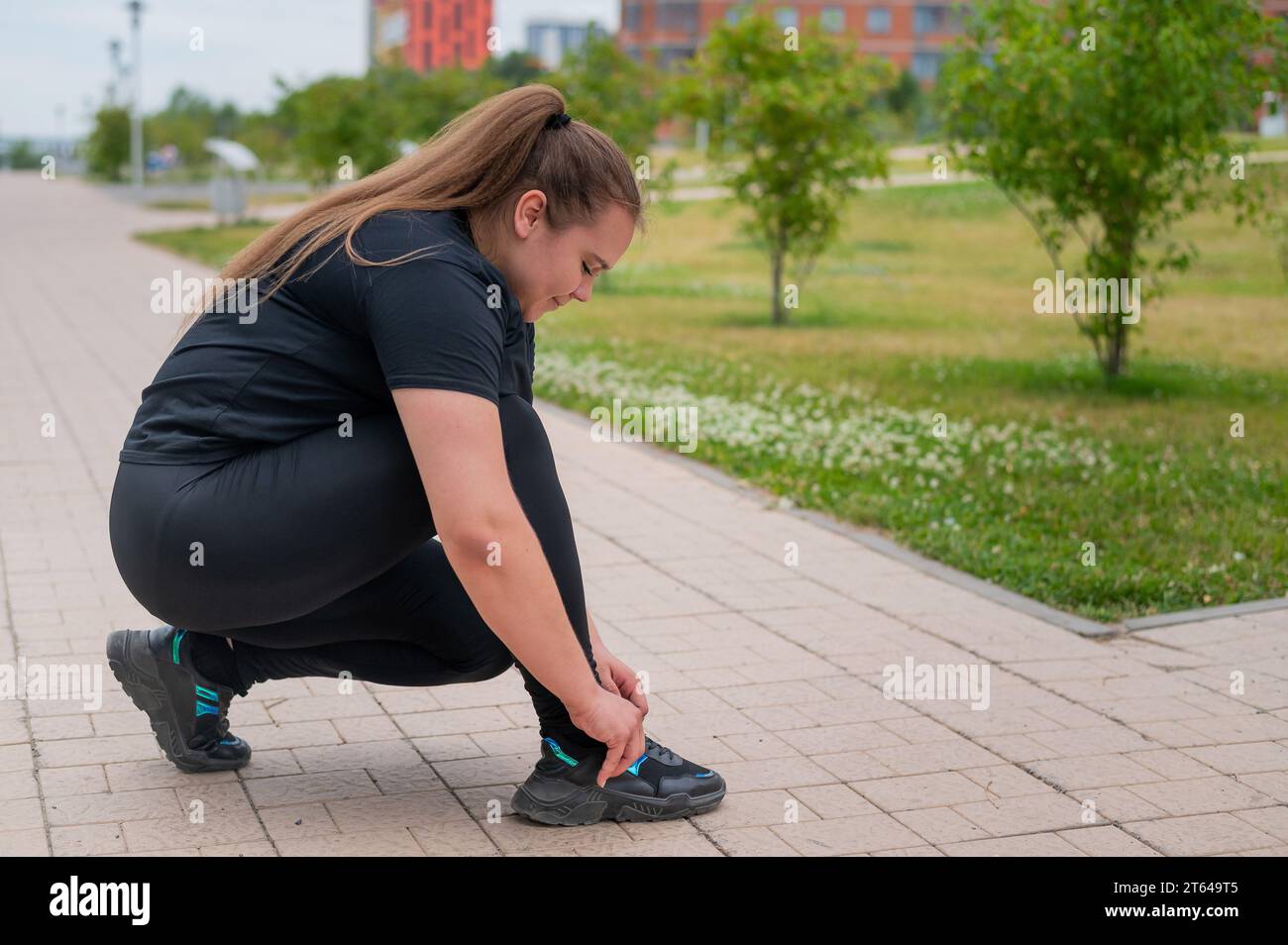 Mujer joven alegre en traje de deporte está de pie después de hacer  ejercicio en las escaleras del edificio urbano al aire libre