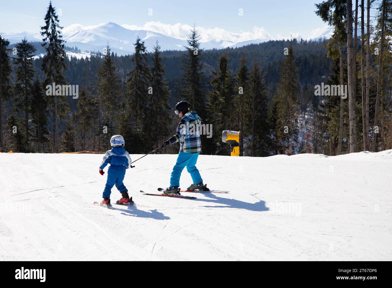 Clase de esquí para niños en la escuela de esquí. Alegrías estacionales, infancia feliz. Clima helado. entrenamiento. estilo de vida saludable. niño pequeño aprendiendo a esquiar con hi Foto de stock