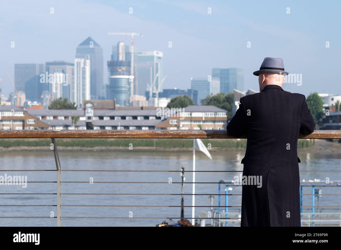 Un hombre mira hacia el río Támesis en Greenwich, Londres hacia los rascacielos de Docklands Foto de stock