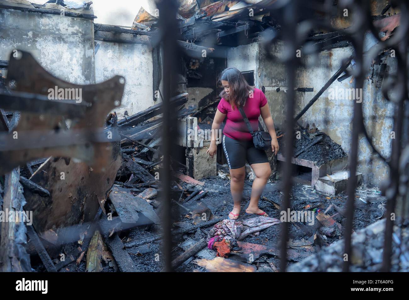 Ciudad de Paranaque, Filipinas. 9 de noviembre de 2023. Una residente busca sus pertenencias dentro de su casa carbonizada después de un incendio en una zona residencial en Paranaque City, Filipinas, 9 de noviembre de 2023. Una madre de 69 años y su hijo de 42 murieron en un incendio de casi tres horas que golpeó un área residencial en la capital filipina el jueves temprano, dijo el funcionario de la Oficina de Protección contra Incendios de Filipinas. El incendio destruyó al menos 20 casas, afectando a alrededor de 40 familias. Los cuerpos de las dos víctimas fueron encontrados en el baño y en la sala de estar, dijo. Crédito: Rouelle Umali/Xinhua/Alamy Live News Foto de stock